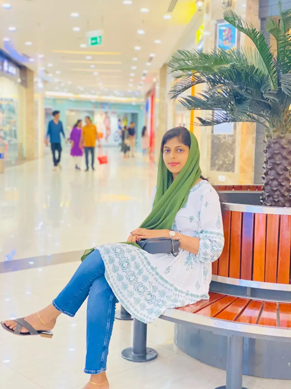 A lady sitting on a bench looking at camera with a smile on face